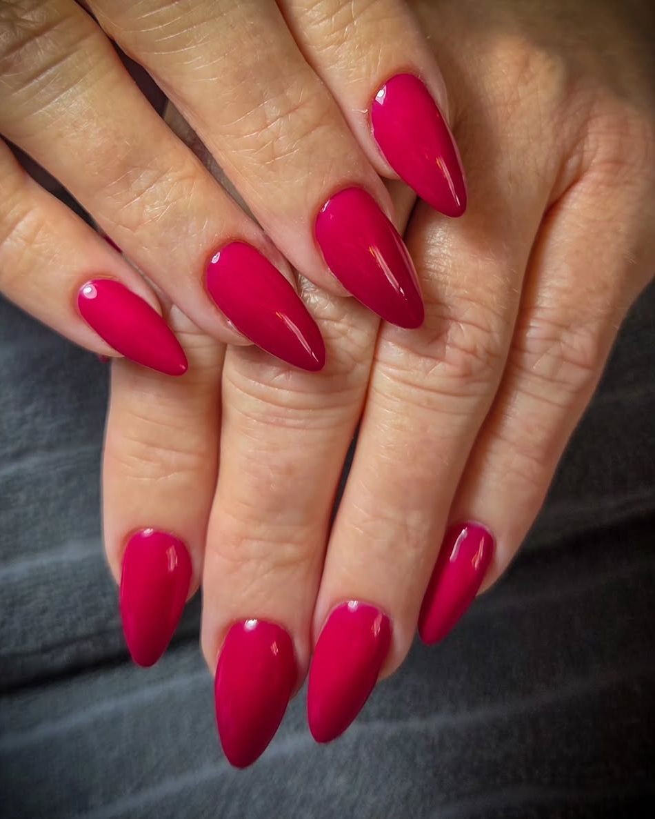 Frambozenrode amandelnagels op een grijze handdoek
